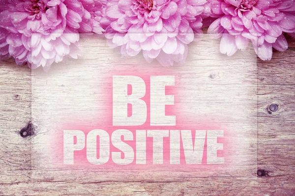 Pink flowers on wooden with word Be Positive