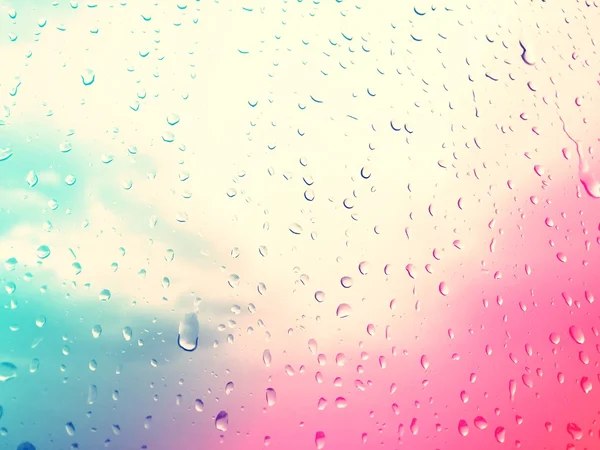Raindrops on glass window, colorful sky background retro style f