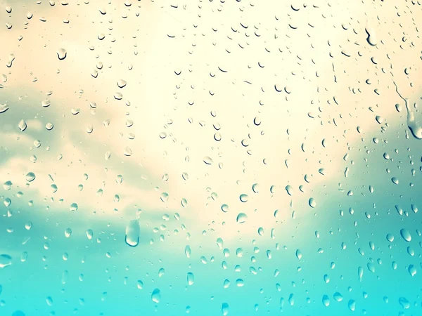 Raindrops on glass window, grey blue sky background, retro style