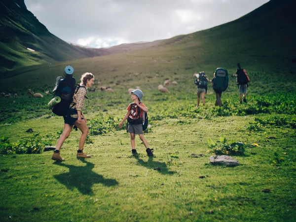 Family hiking in the mountains. A young happy mother and her son take a hike together in the mountains on a beautiful summer evening. Smile and enjoying their time together