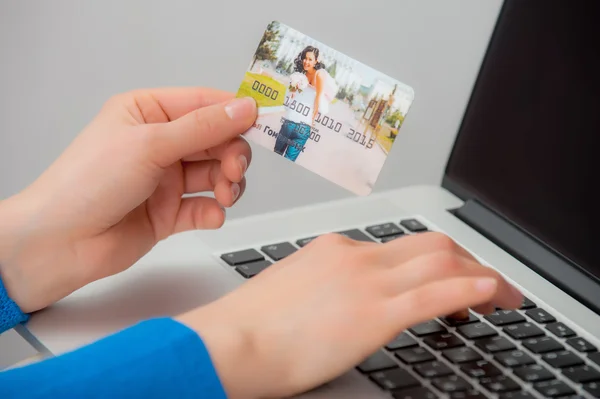 Hands holding credit card and using laptop.