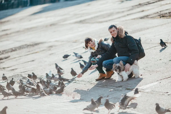 Couple feeding doves at the street.