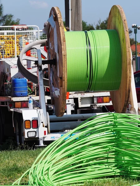 Green NBN fiber optic cable piled up behind an installation truck