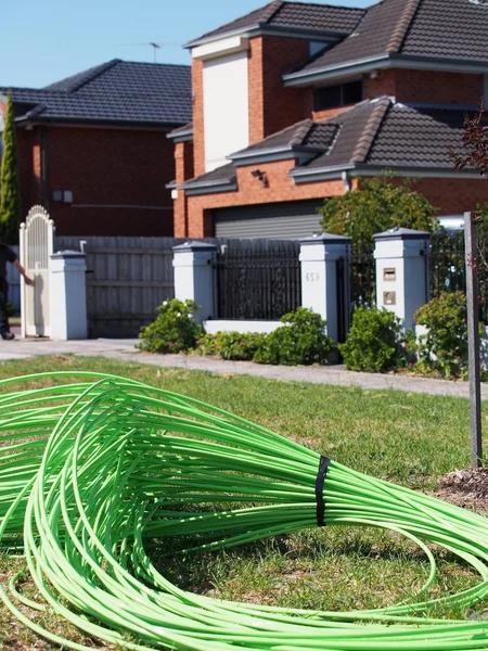 Green fiber optic cable piled in front of residential housing