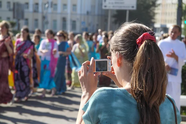 Young woman photographing a group of hare Krishna
