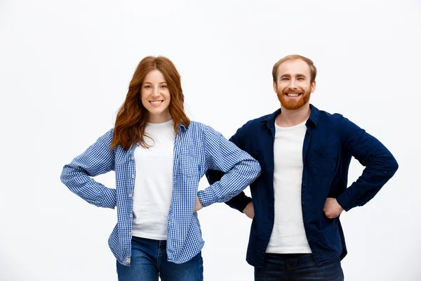 Cheerful redhead girl and boy standing over white background