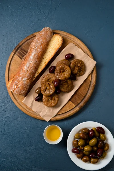 Bread long loaf, fig and dates on wooden board