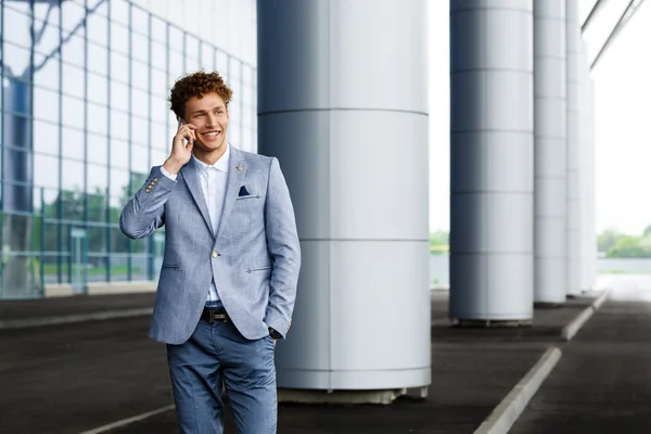 Picture of handsome young redhaired businessman talking on phone smiling
