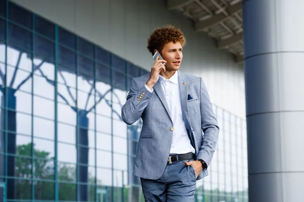 Picture of handsome young redhaired businessman  talking on phone looking aside