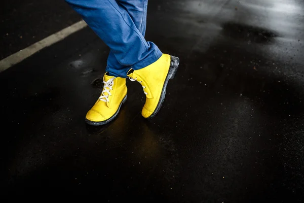Yellow mans shoes over wet rainy street background