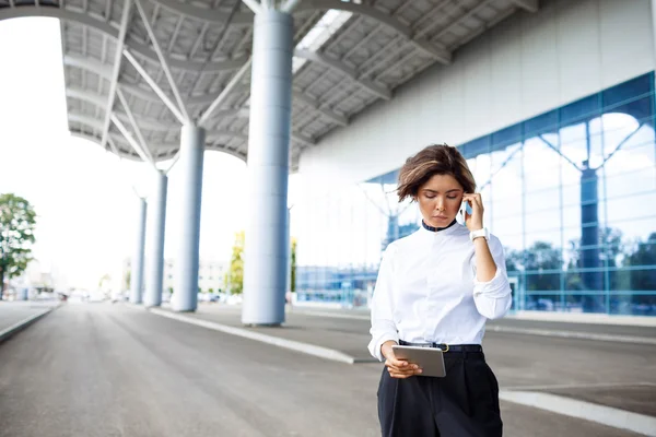 Young successful businesswoman speaking on phone, standing near business centre.