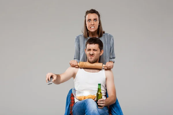 Young beautiful woman angering with man drinking beer, watching football.