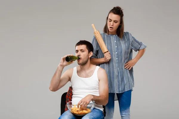 Young beautiful woman angering with man drinking beer, watching football.