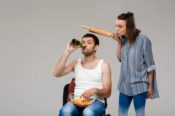 Young beautiful woman angering with man drinking beer, watching football.