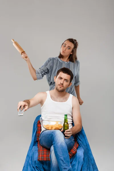 Young beautiful woman angering with man drinking beer, watching football.