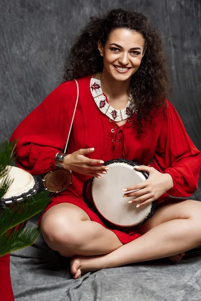 Woman in red dress playing drum