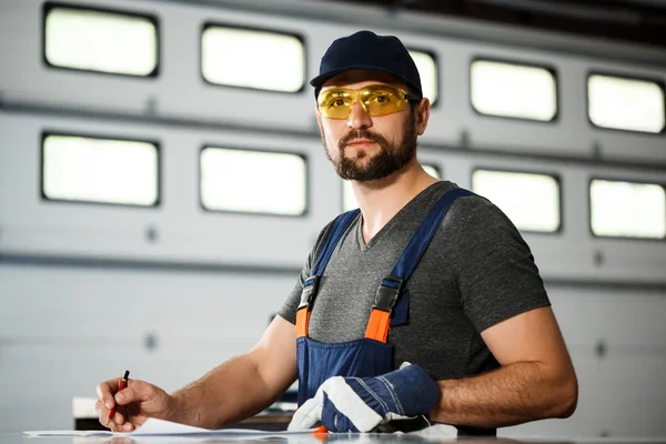 Portrait of worker in overalls, steel factory background.