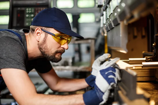 Portrait of worker near metalworking machine, steel factory background.