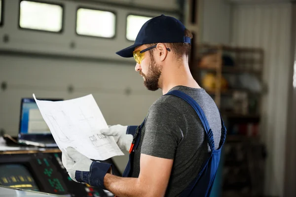 Portrait of worker in overalls, steel factory background.