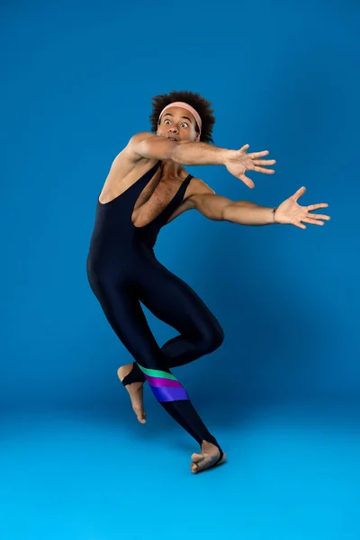 Sportive african man training, fooling over blue background.