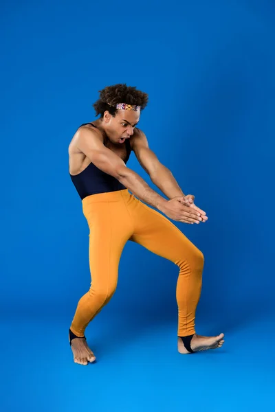 Sportive african man training martial poses over blue background.