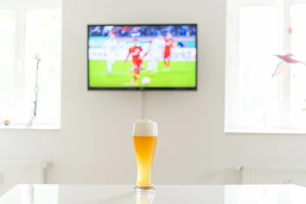Soccer player on television and a glass of wheat beer on a table
