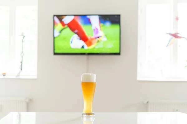 Soccer scene  on television and a glass of wheat beer on a table