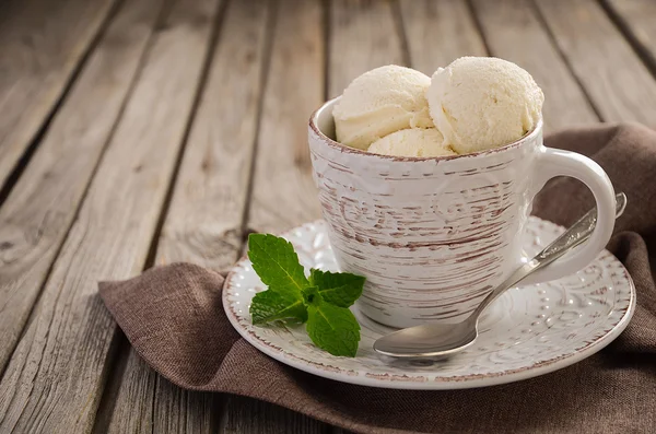 Vanilla ice cream in cup on rustic wooden background