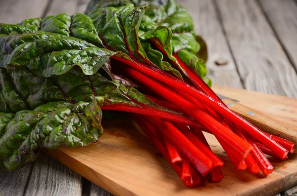 Fresh red chard leaves on wooden background