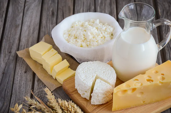 Fresh dairy products. Milk, cheese, butter and cottage cheese with wheat on the rustic wooden background.
