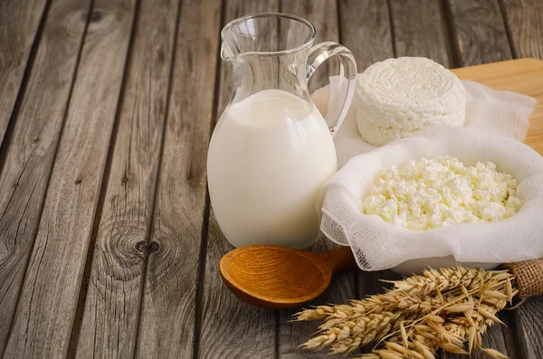 Fresh dairy products. Milk and cottage cheese with wheat on the rustic wooden background.