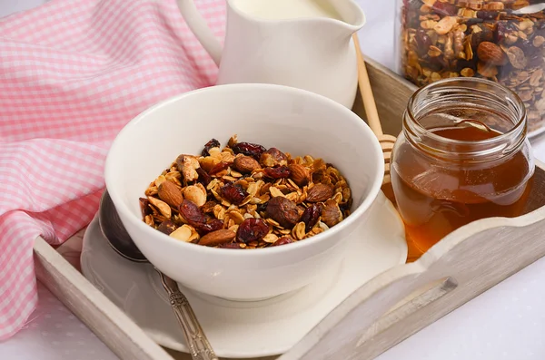 Homemade granola with nuts and dried cranberries with milk and honey.