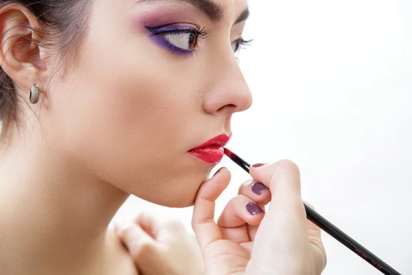 Stylist makes professional lips makeup.