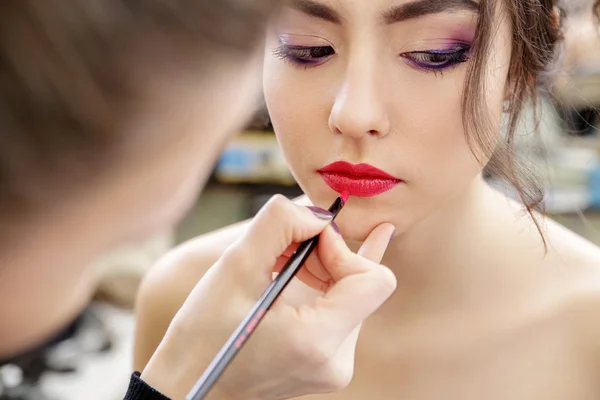 Stylist makes professional lips makeup.