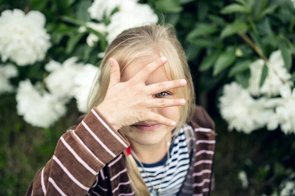 Beautiful blond girl hiding behind his hand.