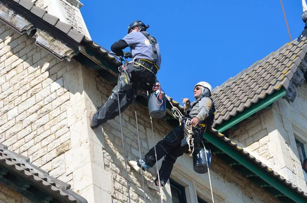 Abseiling building maintenance workers at work.