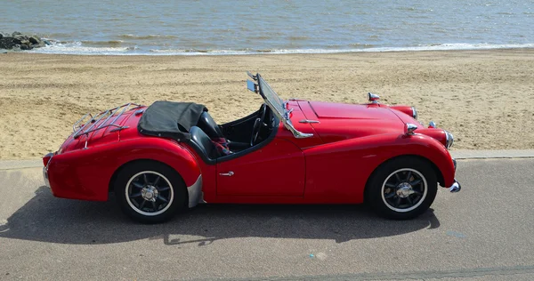 Classic Red MGA Open Top Sports car parked on seafront promenade.