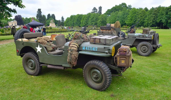 : World War 2 Jeeps with  mounted Machine guns parked on grass.