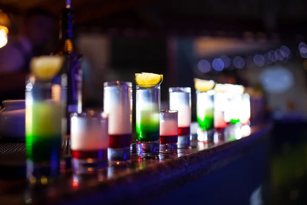 Collection of colorful shots with lemon on bar;