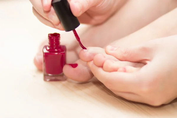 Self pedicure with red nail polish