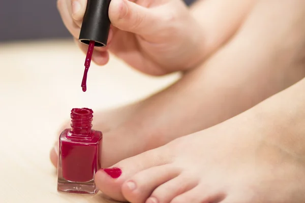 Self pedicure with red nail polish