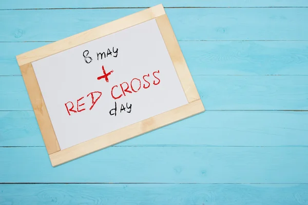 Red Cross Day , lettering on white desk, blue background