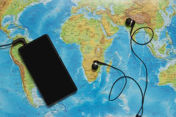 Touristic map of the world, smart phone with earphones