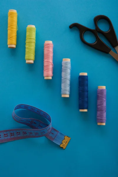 The threads, meter tape, scissors on a blue background top