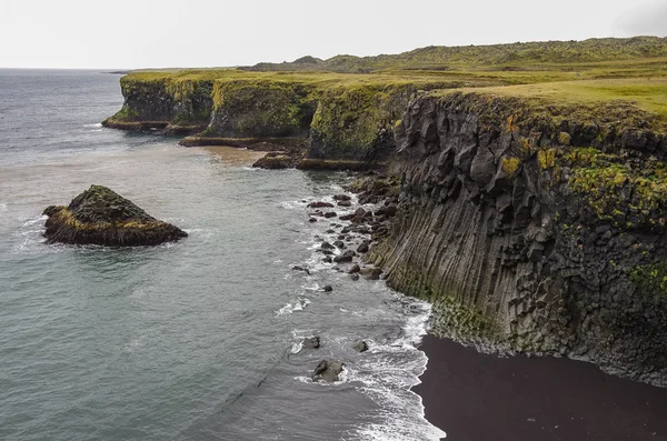 Atlantic ocean and black rock cliff of western Iceland coast