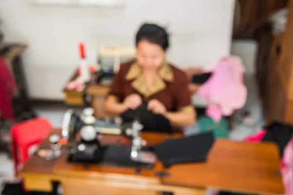 Blurred image of seamstress working on sewing machine