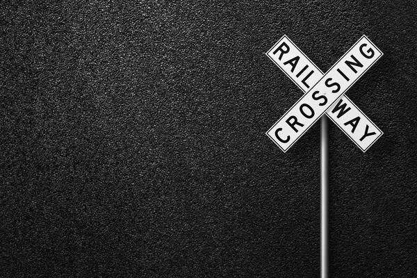 Road sign on a background of asphalt. RAIL WAY CROSSING. The texture of the tarmac, top view.