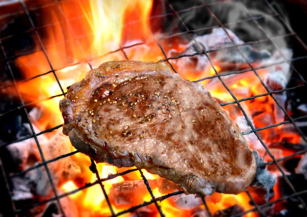 Grilling pepper steaks on flaming