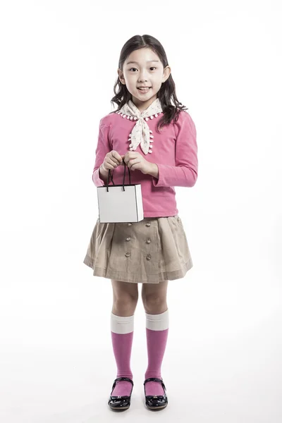 A kid wearing pink blouse, white scarf with paper bag.