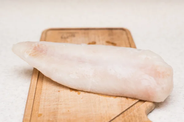 Frozen and thawed fish fillet on the cutting board